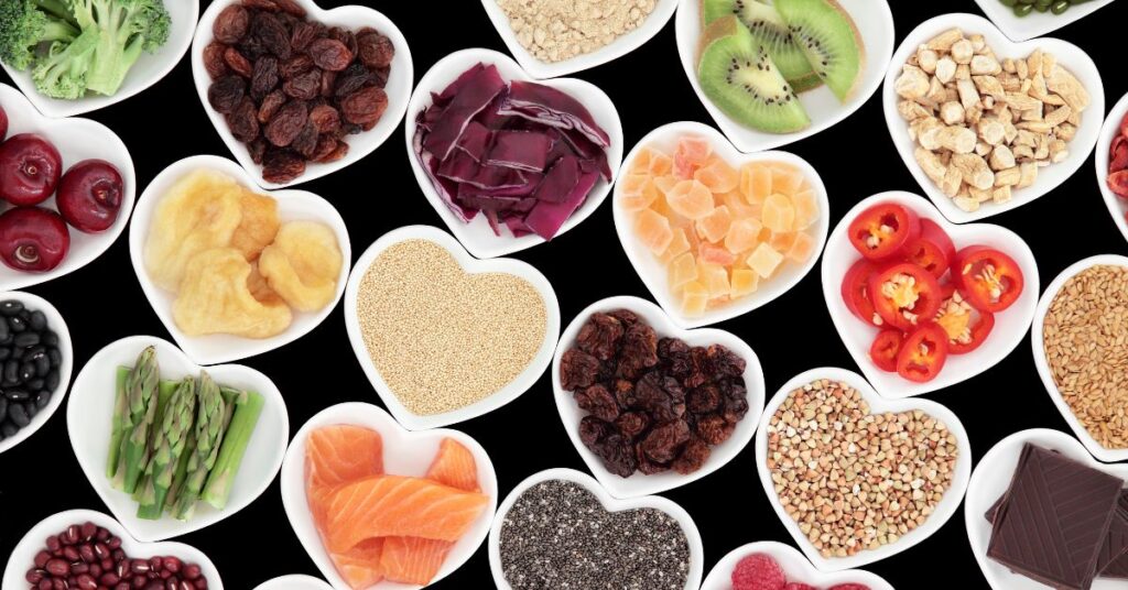 Heart-shaped dishes filled with colorful whole foods like fruits, vegetables, grains, and salmon, symbolizing a nourishing, food-first approach to healing.