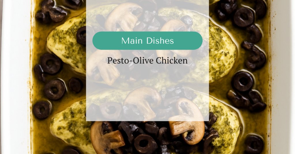 Baked chicken breasts in pesto sauce, topped with sautéed mushrooms and chopped olives in a white ceramic baking dish.
