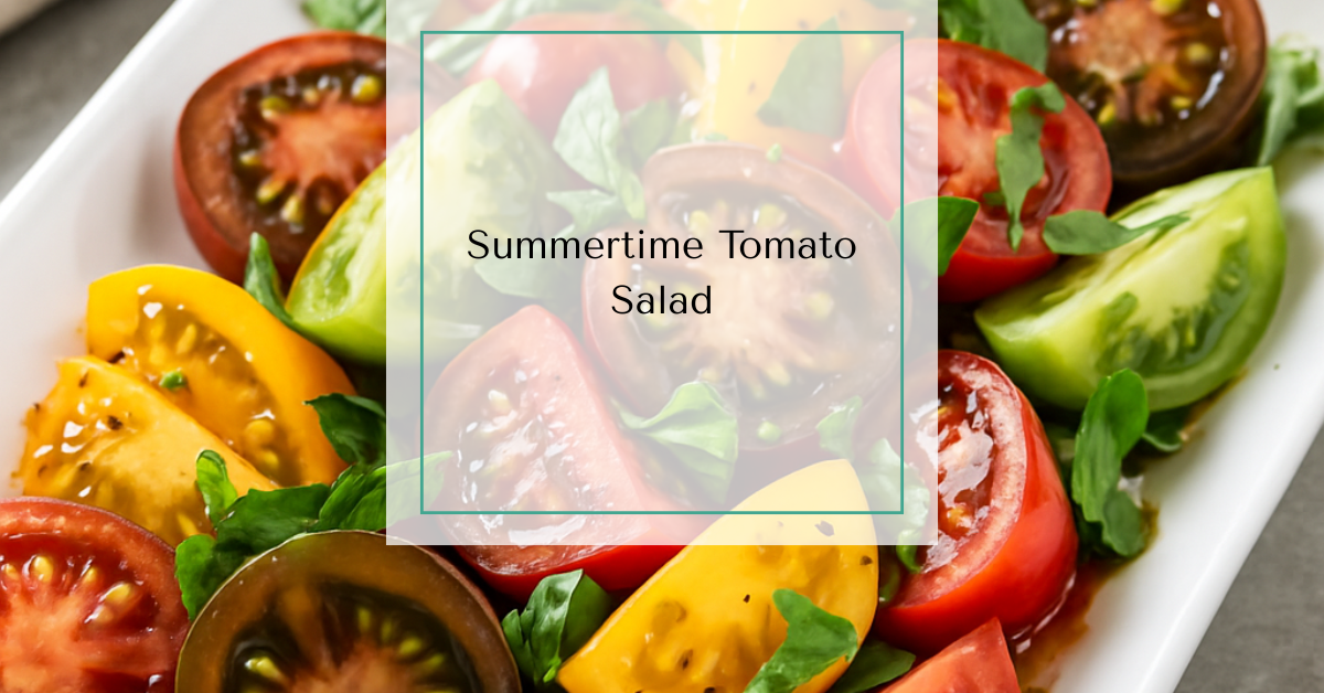 A close-up photograph of a colorful tomato salad with fresh basil and a balsamic vinaigrette drizzle, served on a white rectangular platter.