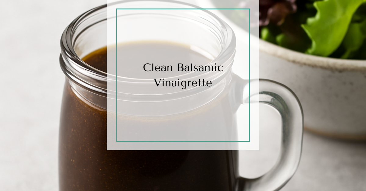 A glass jar of homemade balsamic vinaigrette beside a bowl of mixed salad greens.