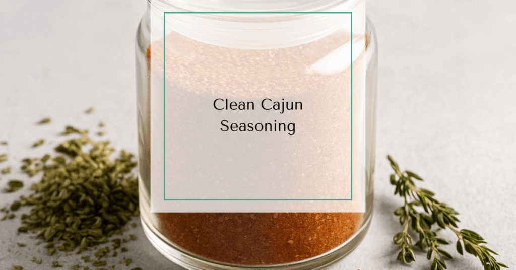 A glass spice jar of Cajun seasoning surrounded by dried herbs and red pepper flakes.