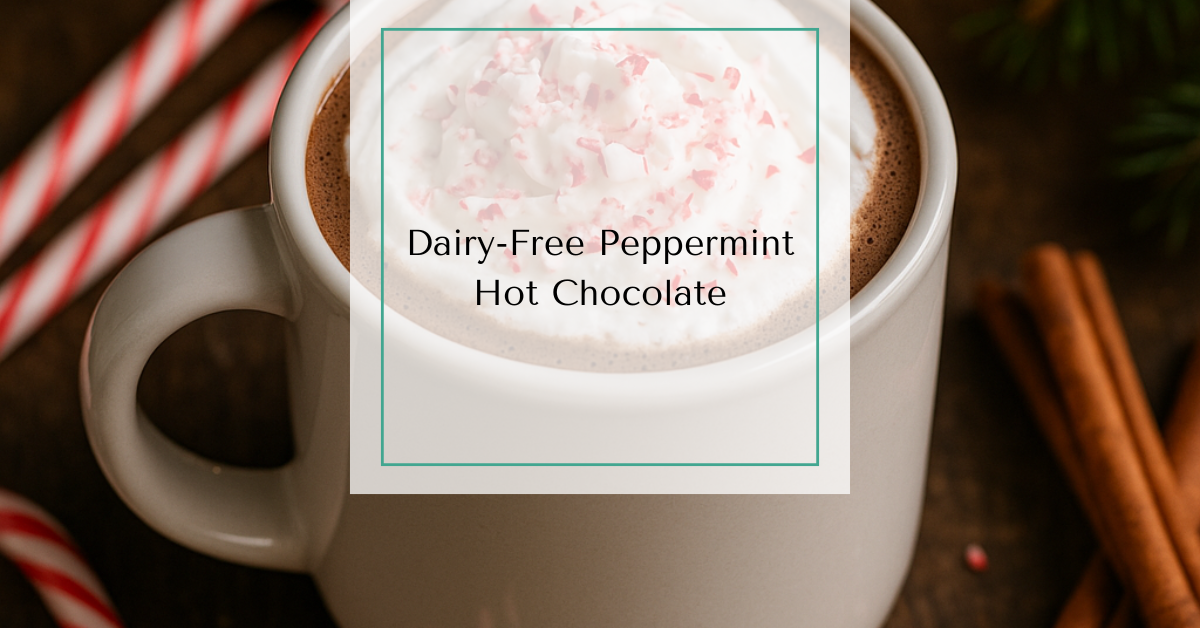 A festive mug of hot chocolate topped with dairy-free whipped cream and crushed candy canes, surrounded by pine branches, holiday lights, and cinnamon sticks.