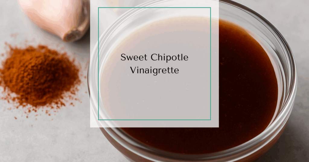 A glass bowl filled with smoky chipotle vinaigrette next to garlic cloves and chili powder.