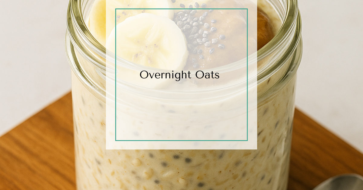 Jar of creamy overnight oats topped with sliced banana, chia seeds, and almond butter, resting on a wooden board beside a spoon.