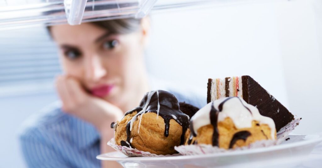 Woman looking into the refrigerator at a tray of desserts