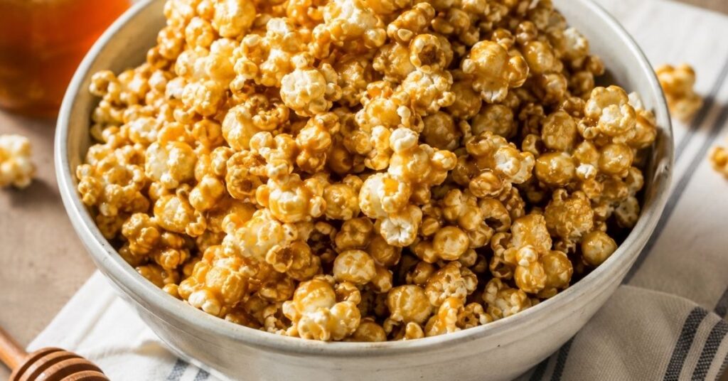 Homemade clean eating caramel popcorn coated with honey and nut butter in a ceramic bowl.